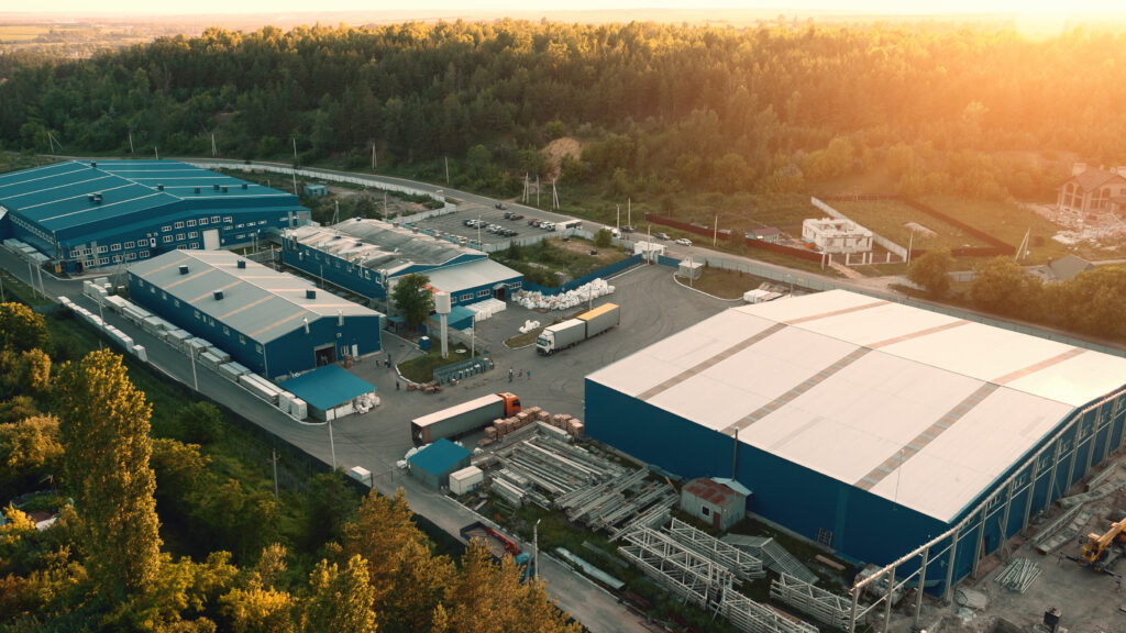 Aerial view of warehouse storages or industrial factory or logistics center from above. Aerial view of industrial buildings and equipment machines at sunset